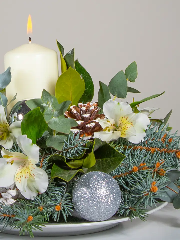 Centrotavola di fiori bianchi elementi natalizi e candela bianca macro